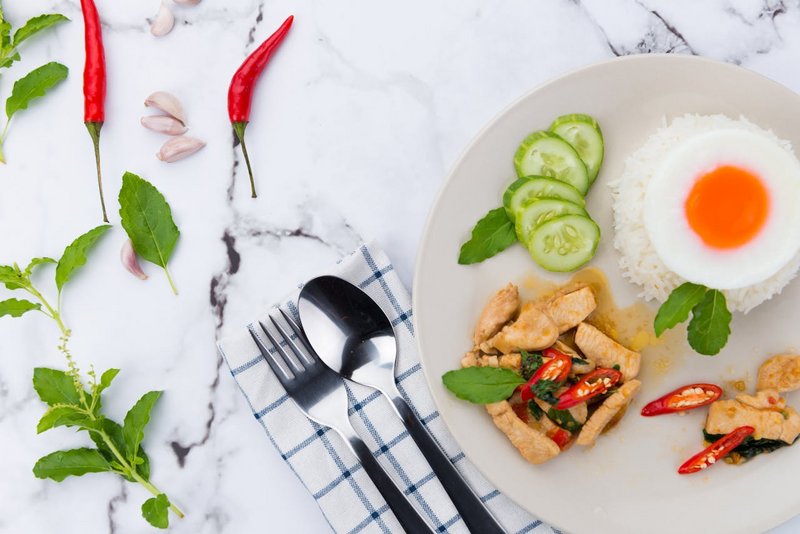 Assorted Thai dishes including curry, noodles, and spring rolls on a shared table
